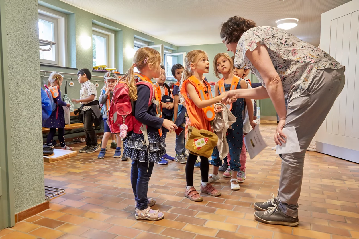 Kinder geben der Kindergarten-Lehrperson die Hand