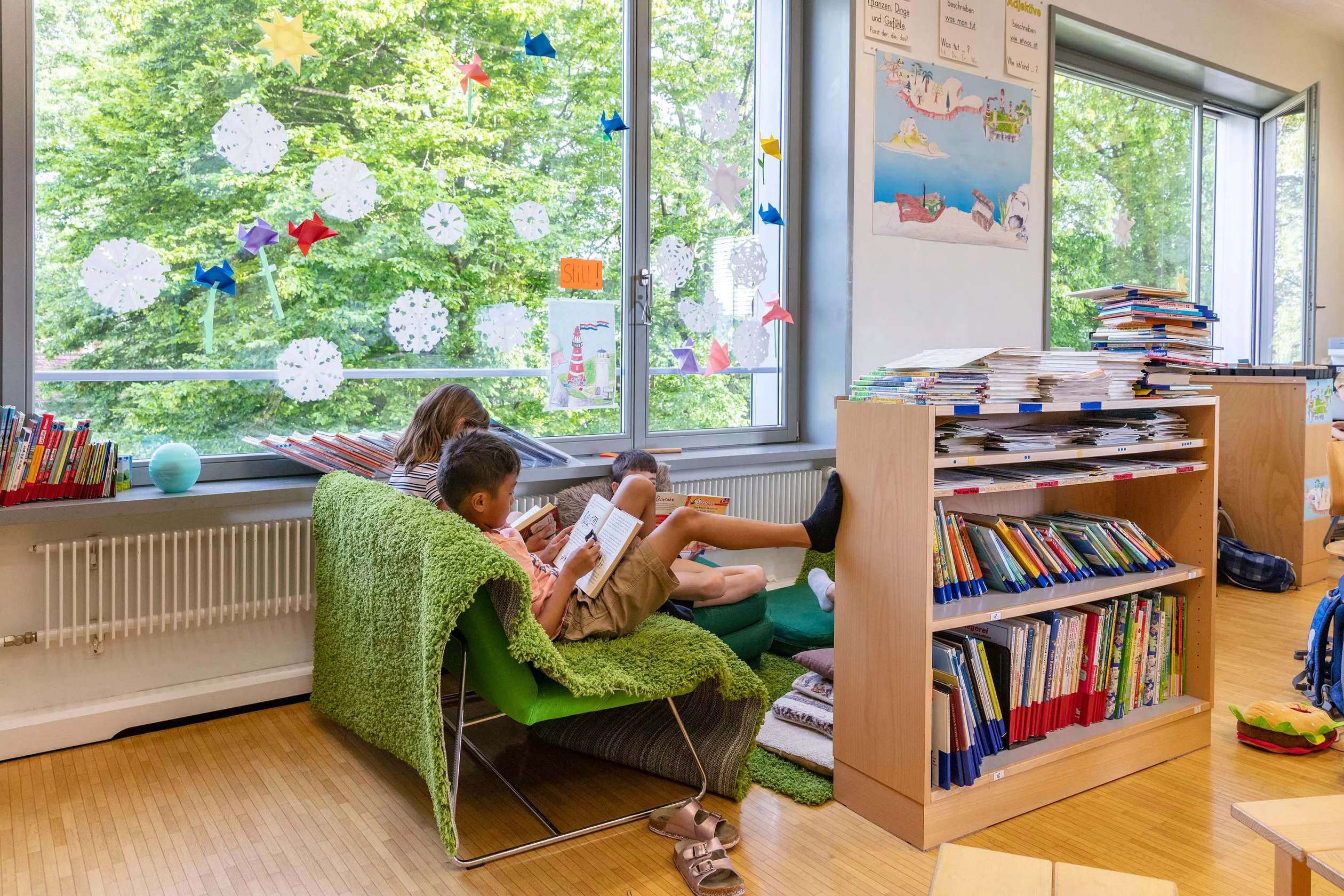 Zwei Kinder lesen auf einem Sessel in der Leseecke.