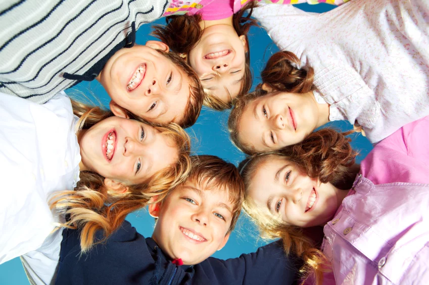 Sechs Kinder strecken die Köpfe zusammen und lachen in die Kamera.