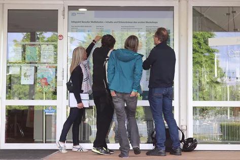 Vier Personen schauen sich eine Infotafel an