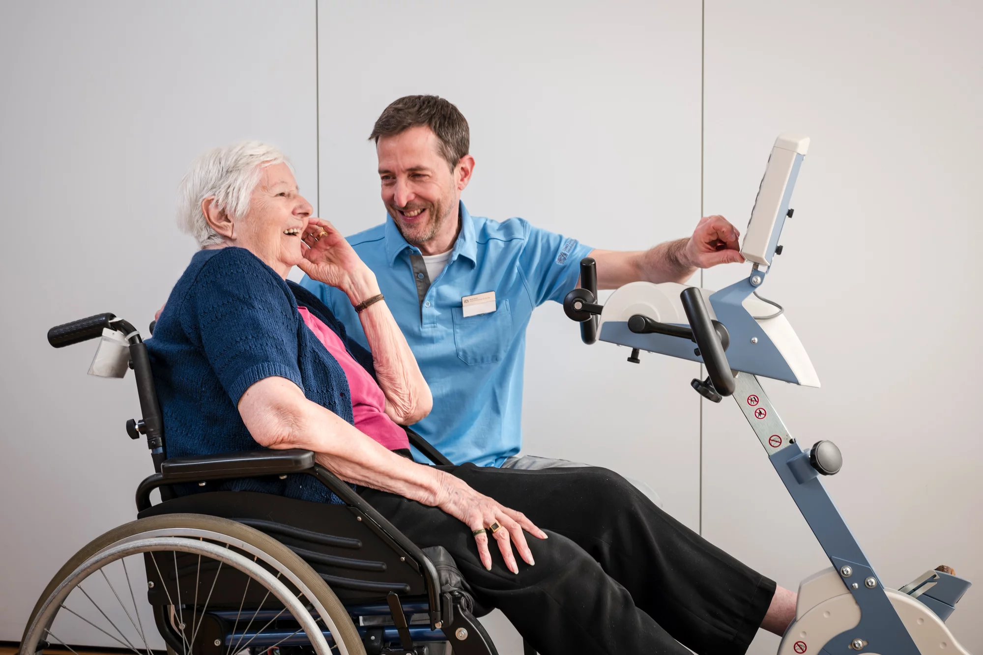 Dipl. Physiotherapeut FH in Ausbildung führt eine Übung mit einer Bewohnerin an einem Gerät durch.