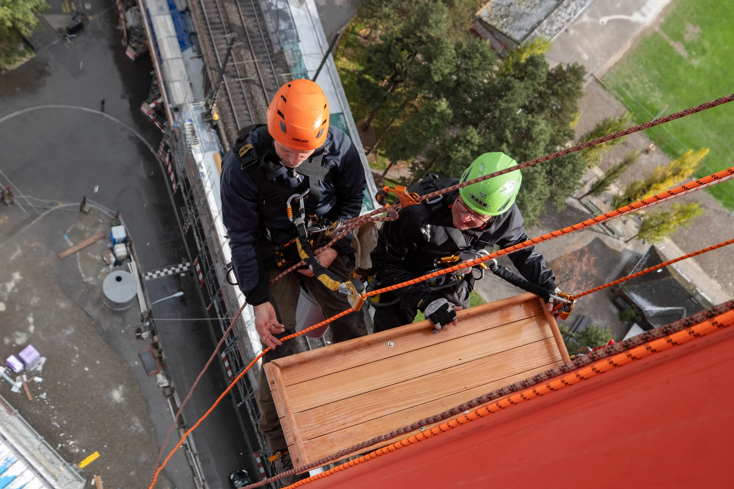 Zwei Personen bringen ein Falkenbrett am Kamin der ehemaligen Kehrrichtverwertungsanlage in Zürich an.