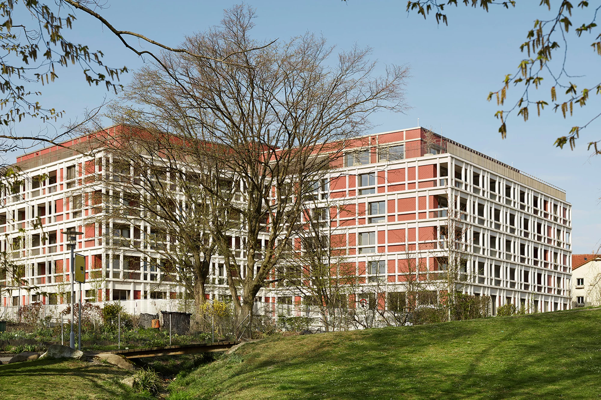 Das Foto wirft einen Blick durch die grüne Umgebung mit Bäumen auf die Fassade des Gesundheitszentrums.