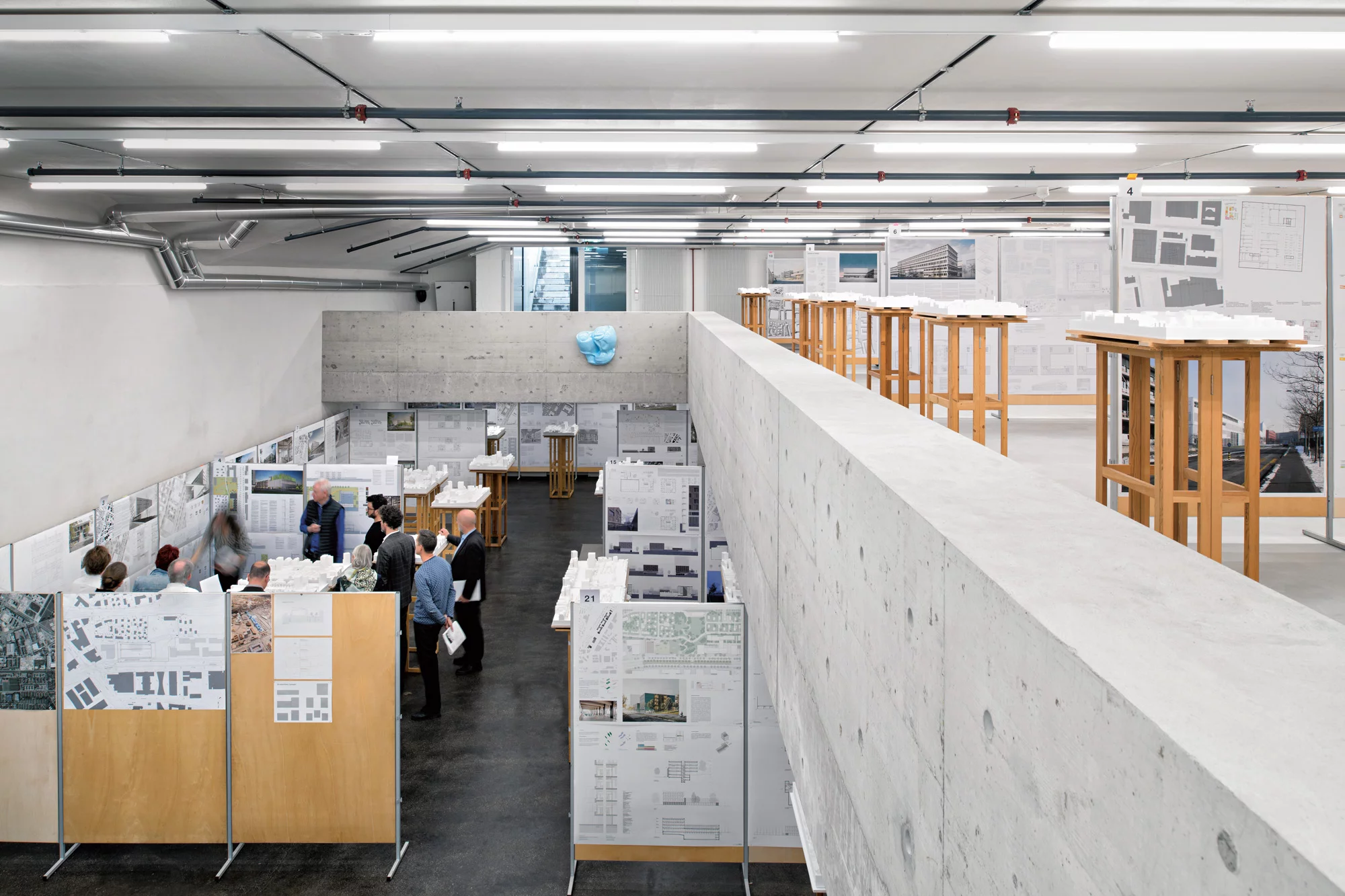 Blick auf eine Jurierung im Jurierungsraum Werd mit aufgehängten Plänen und aufgestellten Architekturmodellen.