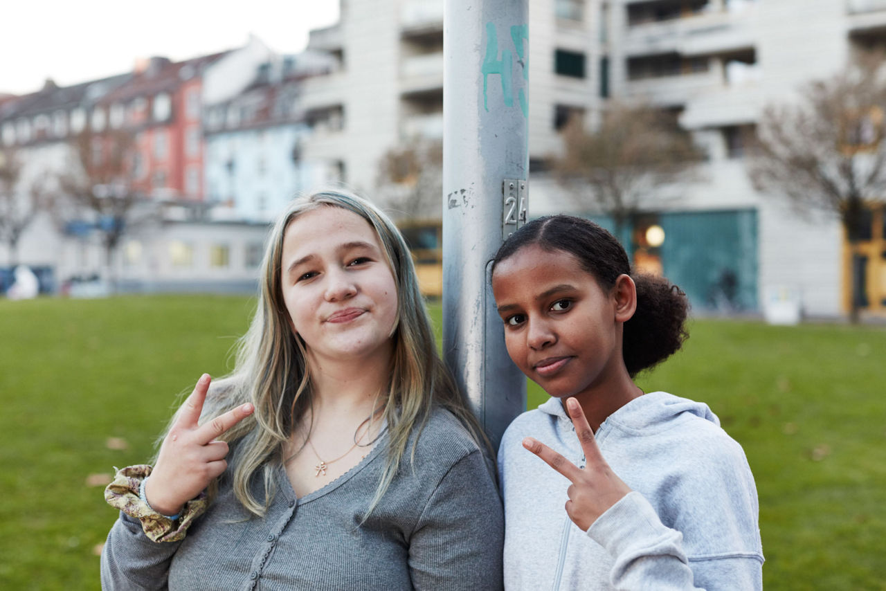 Zwei Jugendliche schauen in die Kamera und machen das Peace-Zeichen mit den Fingern.
