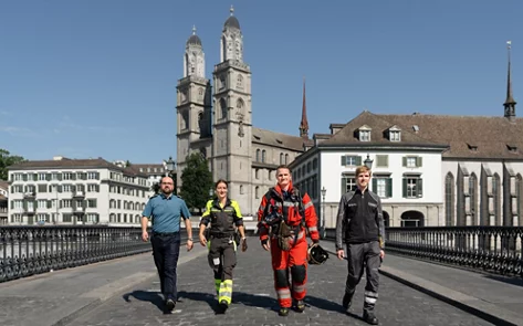 Vier Personen in Uniform gehen im Gleichschritt über eine Brücke