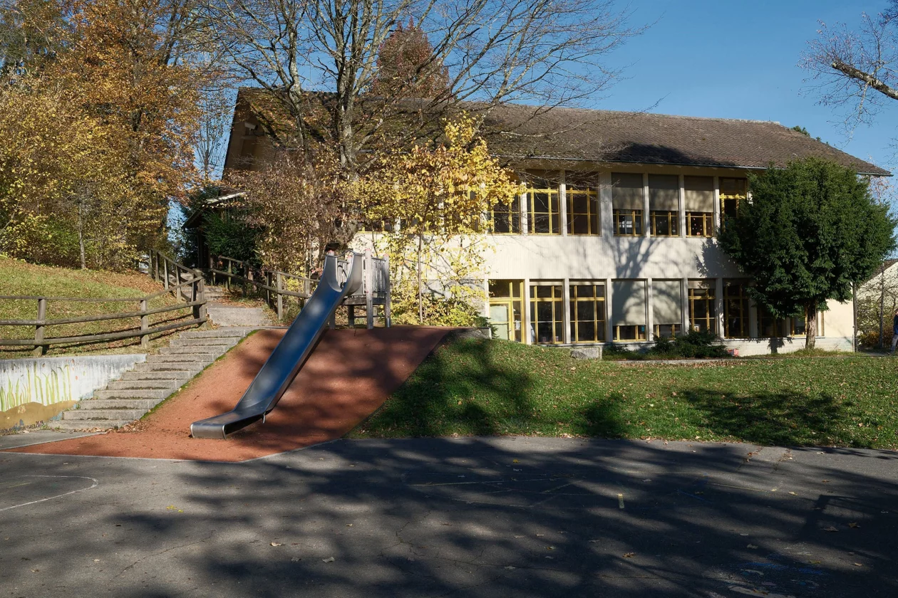 Aussenansicht des Kindergartens Bruderwies mit Spielplatz und Rutschbahn.