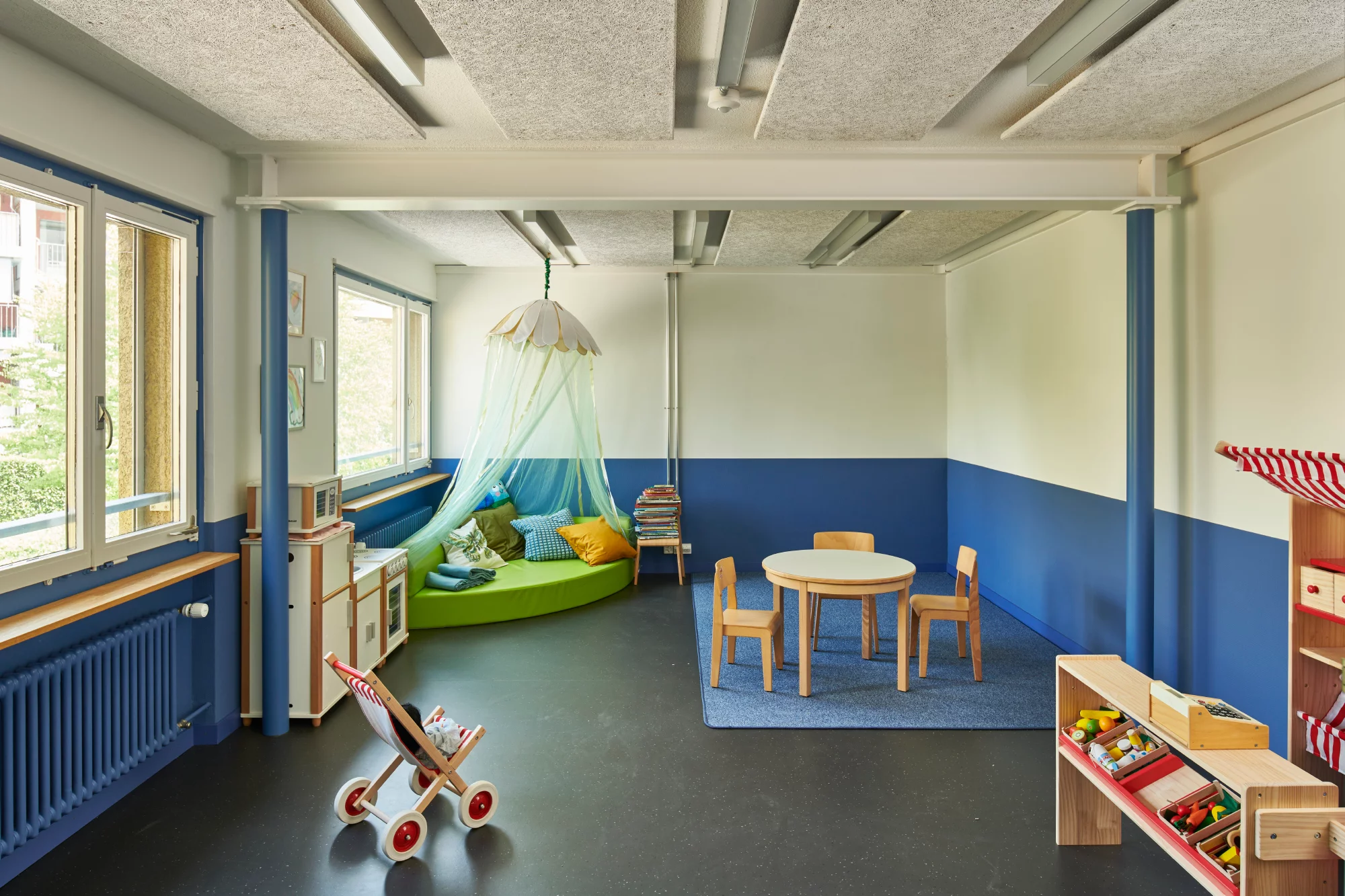Das Foto wirft einen Blick in den Innenraum des möbilierten Kindergartenzimmers mit Spielzeug und Sitzmöglichkeiten.
