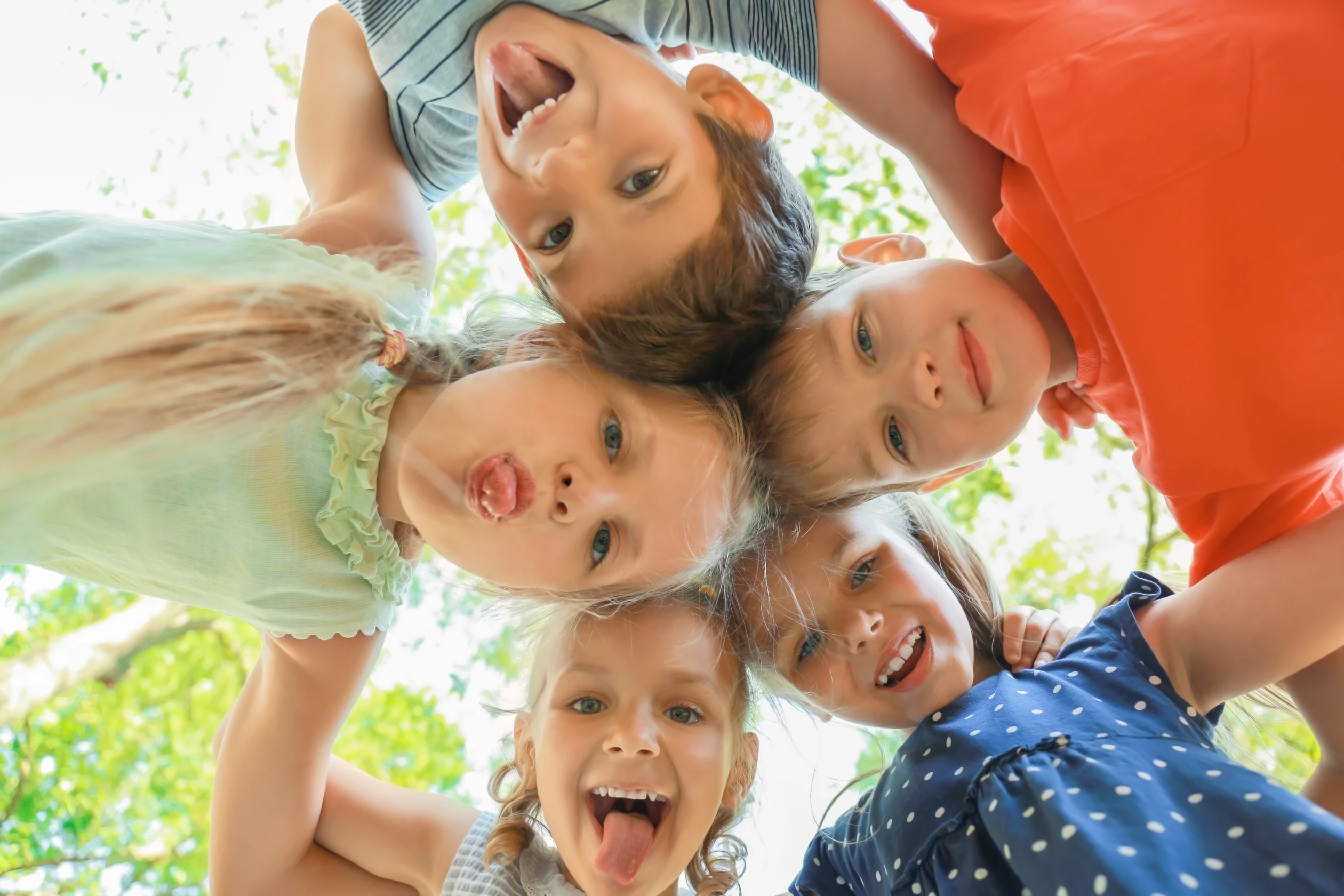 Kinder stehen im Kreis, die Köpfe zusammengesteckt