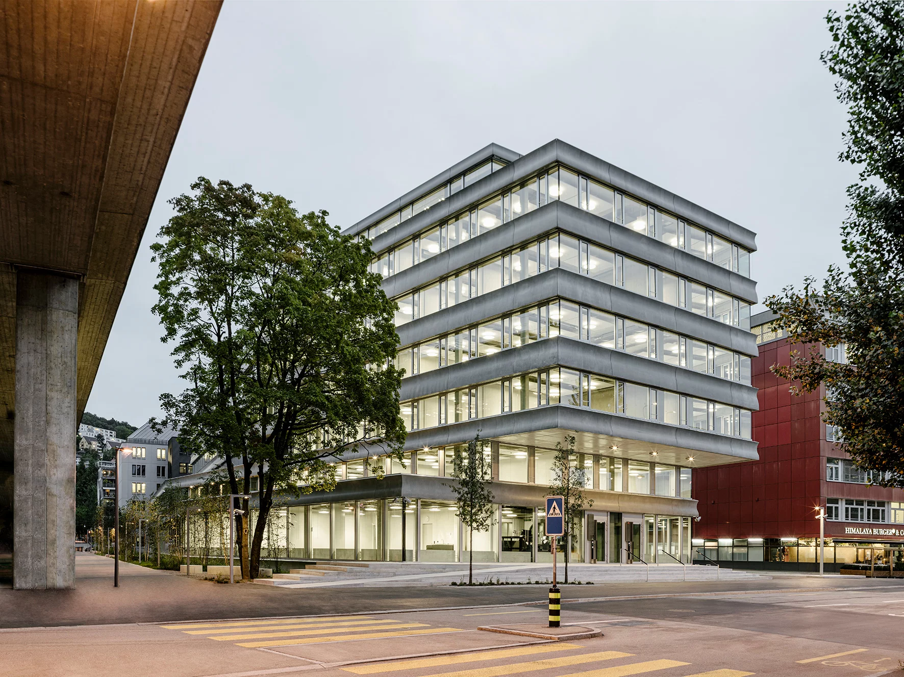 Das Foto wirft einen Blick über die Strasse auf das transparente Gebäude des Neubaus.