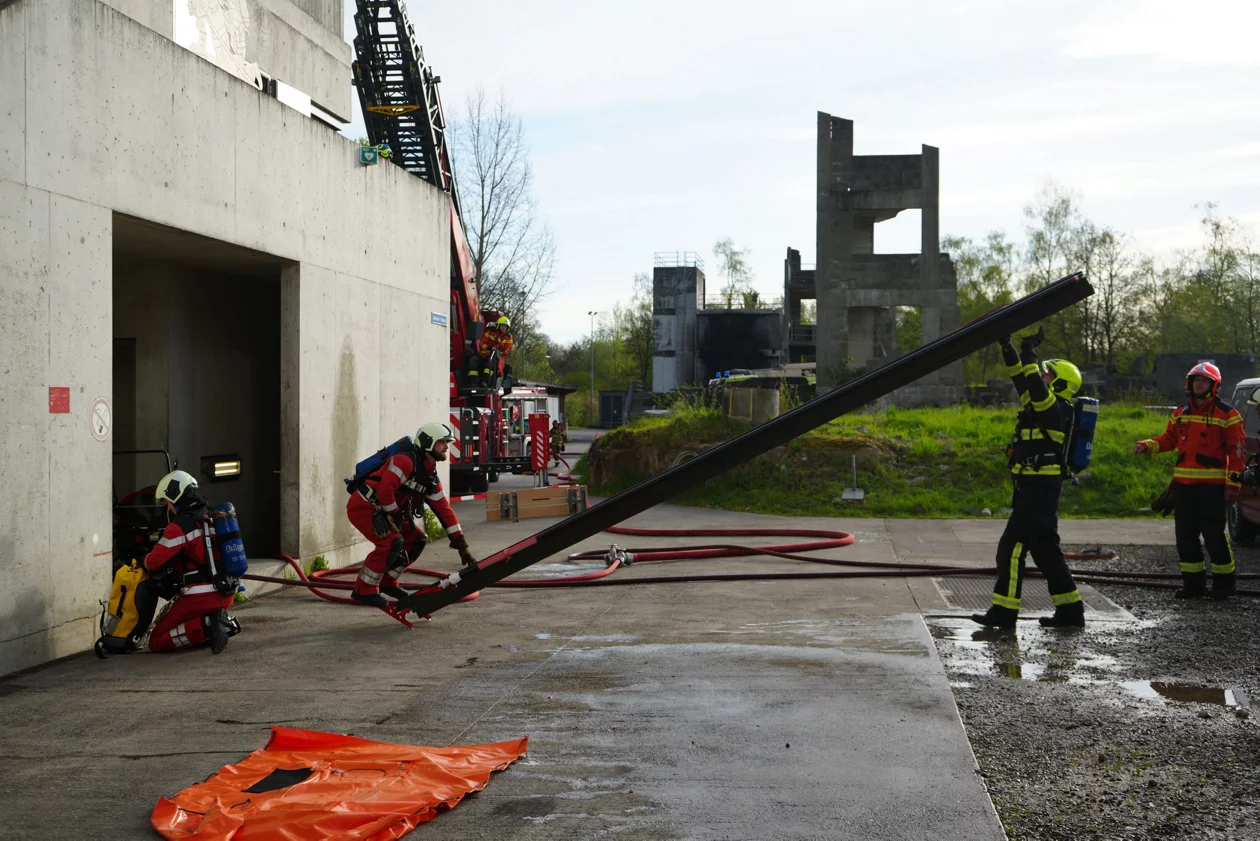 Feuerwehrleute üben eine Schiebeleiter mit Stützen aufzustellen.