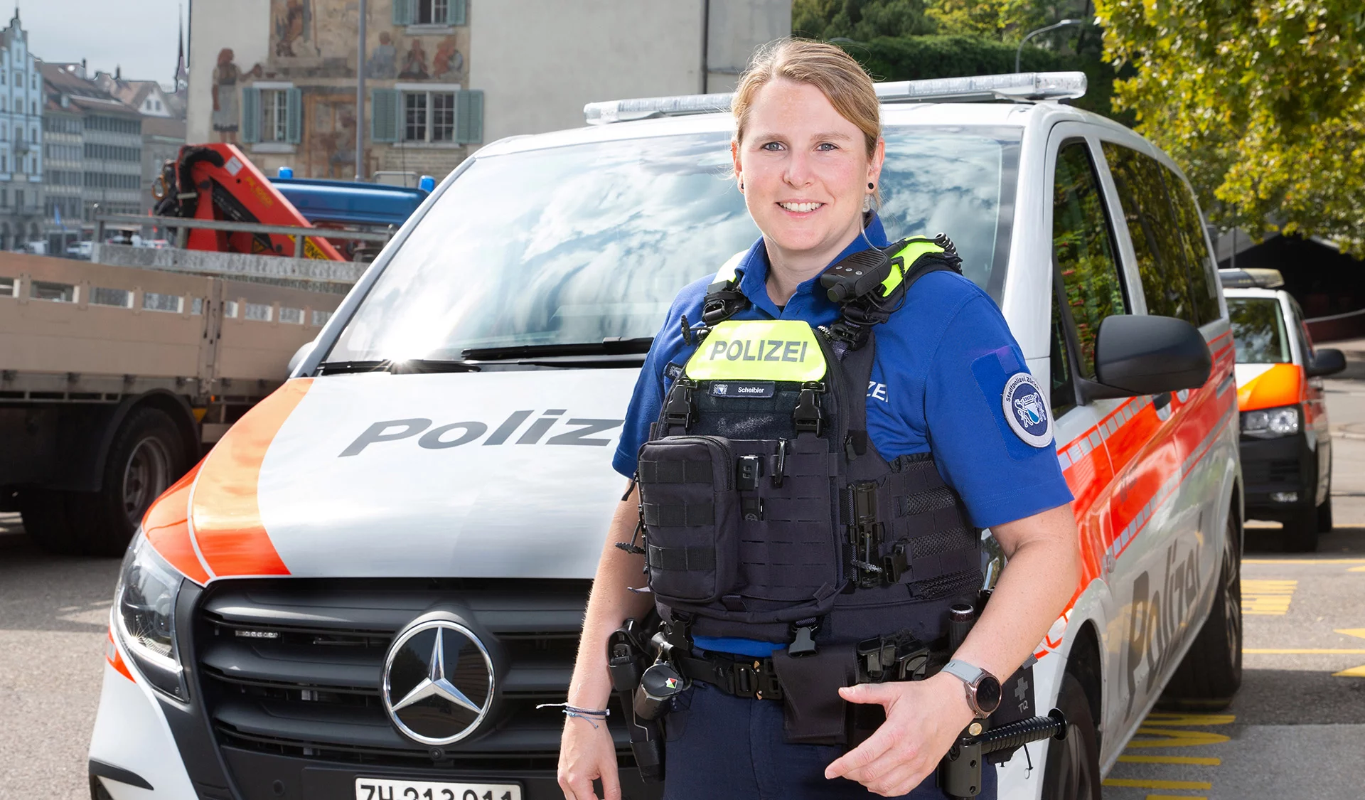 Marina Scheibler in Polizeiunform vor Polizeiauto stehend.
