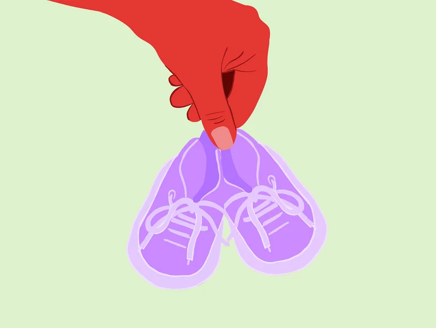 Eine Hand hält ein Paar Babyschuhe