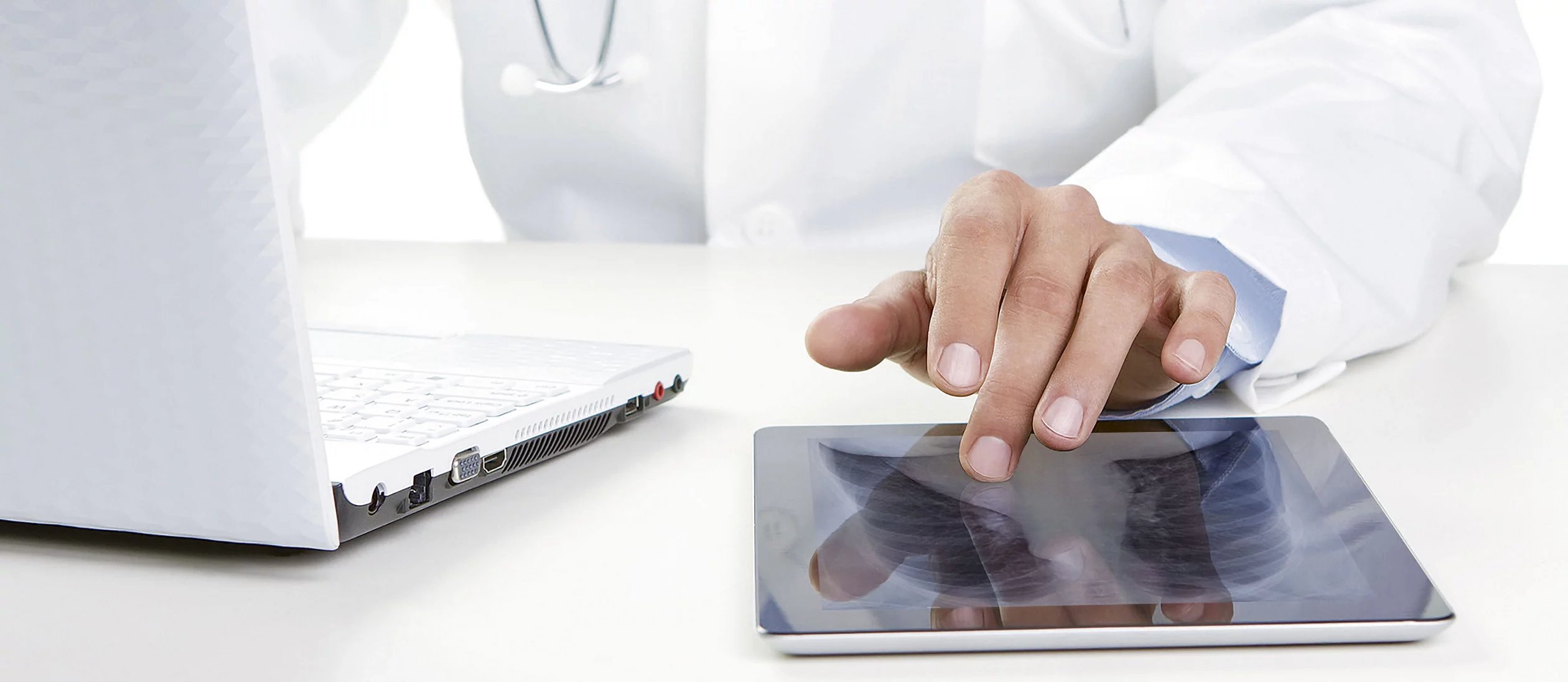 Arzt mit Ipad und Laptop am Arbeiten