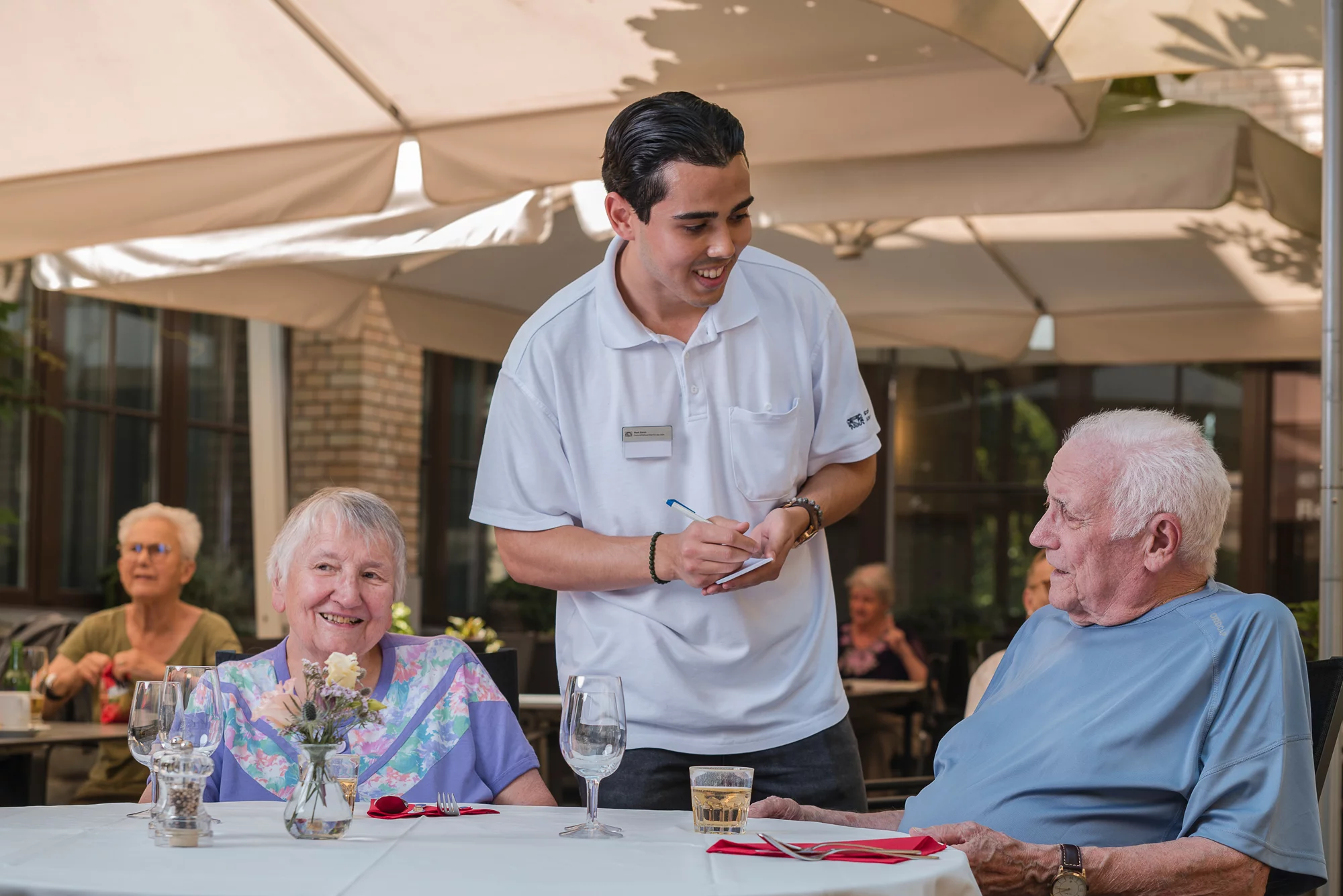 Restaurantangestellter in Ausbildung nimmt die Bestellung eines Bewohners im Restaurant entgegen.