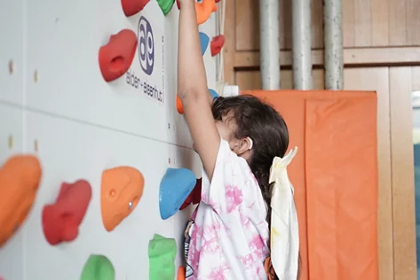 Ein Mädchen Klettert eine Indoor-Kletterwand hoch