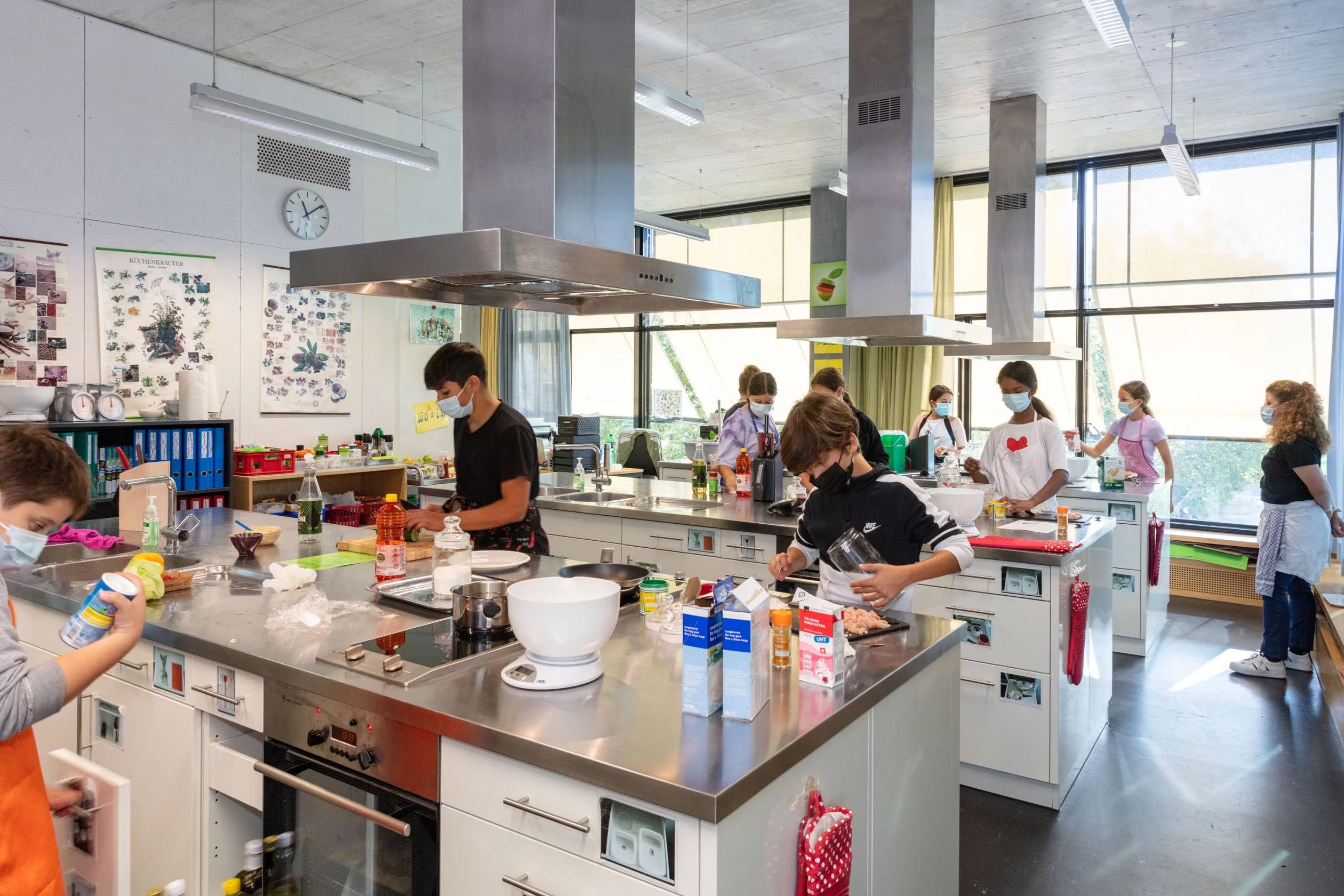 Eine Schulklasse ist in der Schulküche am Kochen.