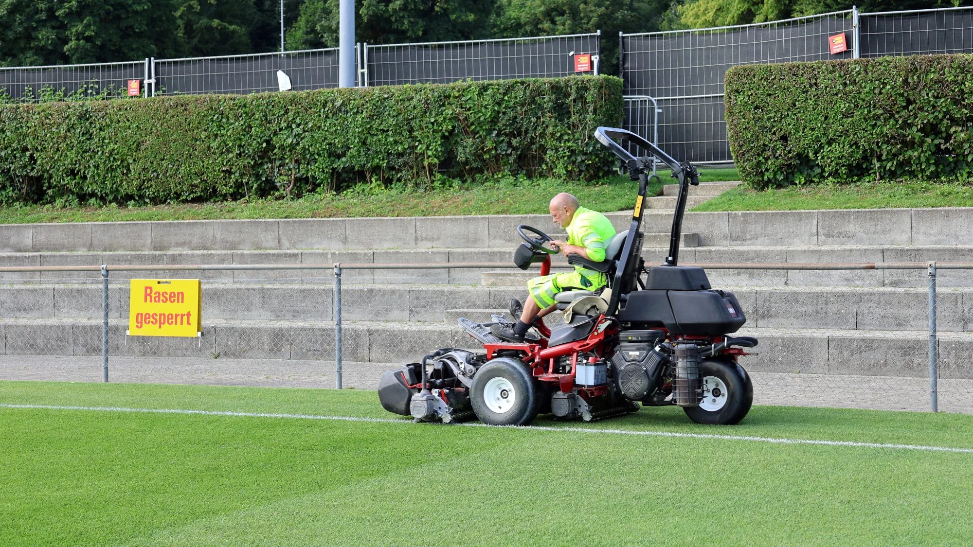 Ein Mitarbeiter von Grün Stadt Zürich mäht den Sportrasen mit einem Spindelrasenmäher.