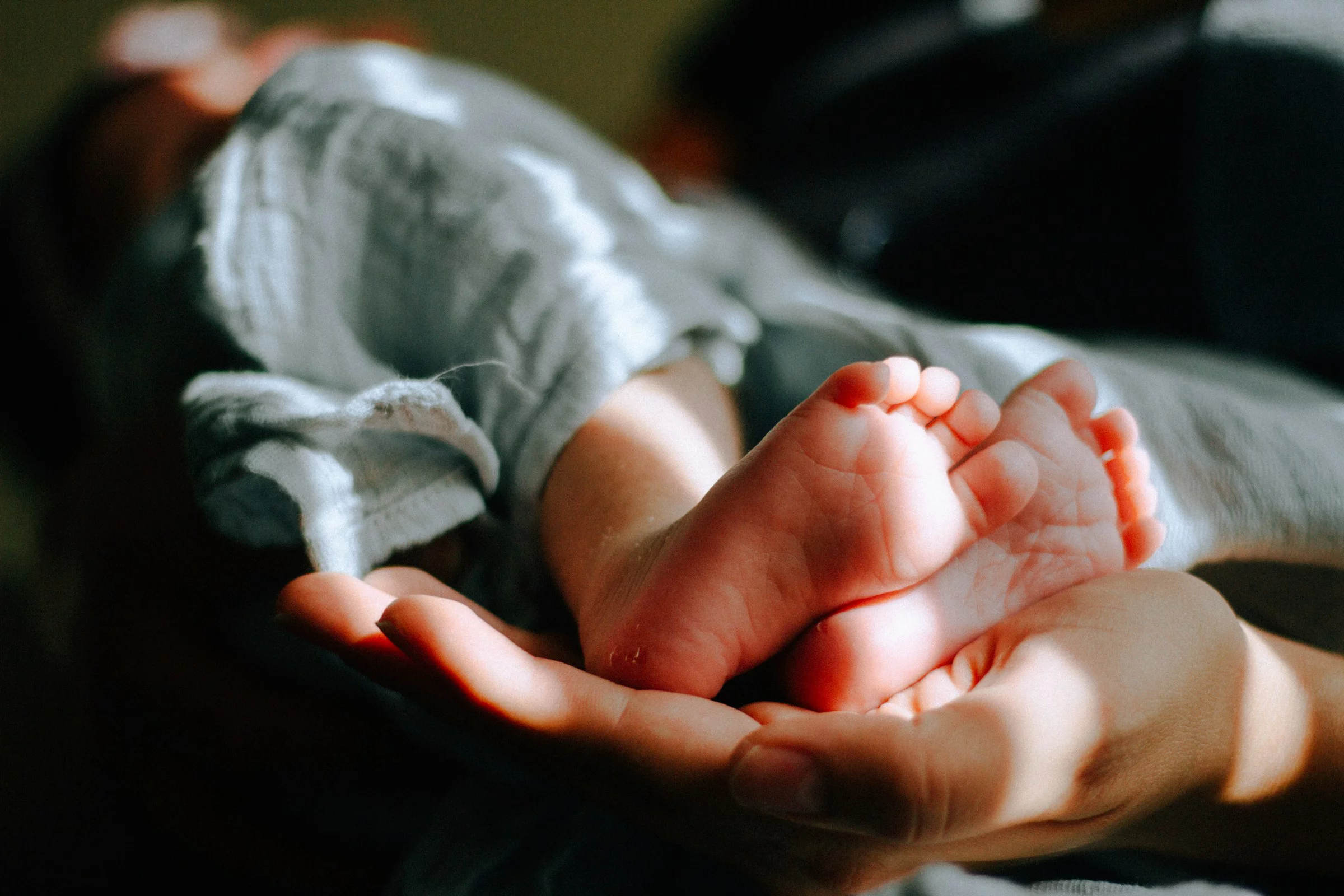 Füsse eines Babies in der Hand einer erwachsenen Person
