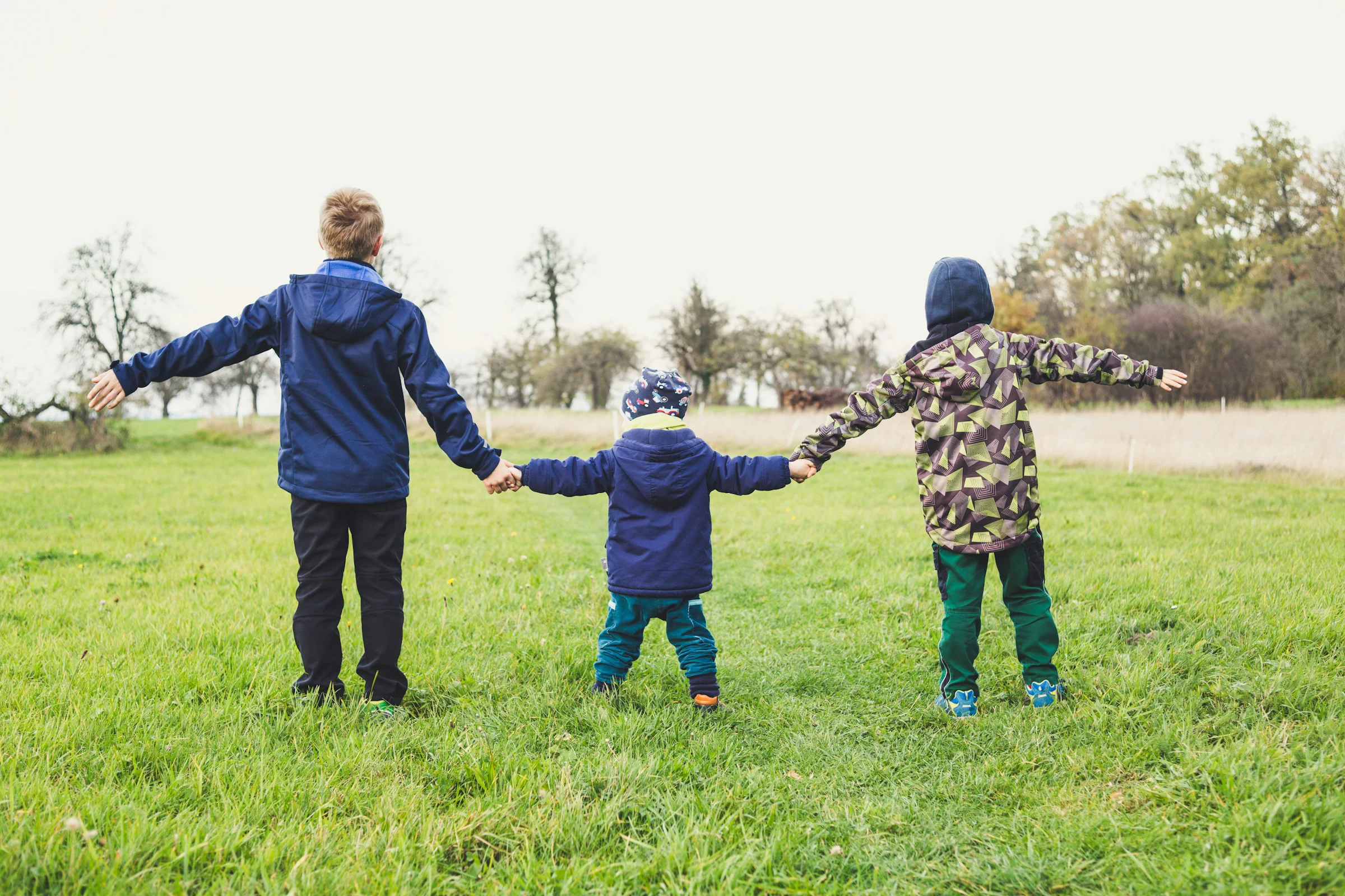 Mutter mit zwei Kinder von hinten auf einer Wiese