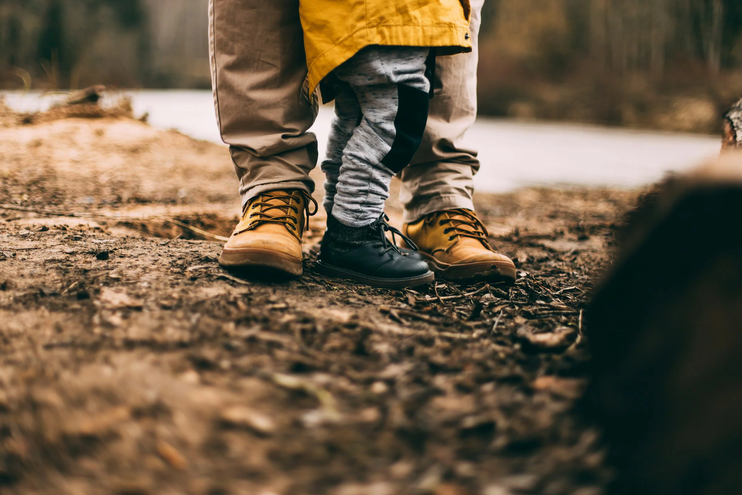 Nahaufnahme von Schuhen eines Kindes und einer erwachsenen Person auf einem Waldboden