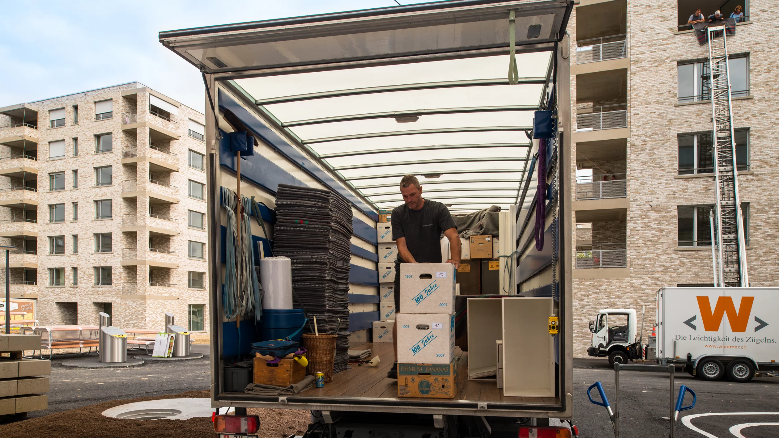 Umzugswagen mit offener Ladefläche vor einem Wohnhaus