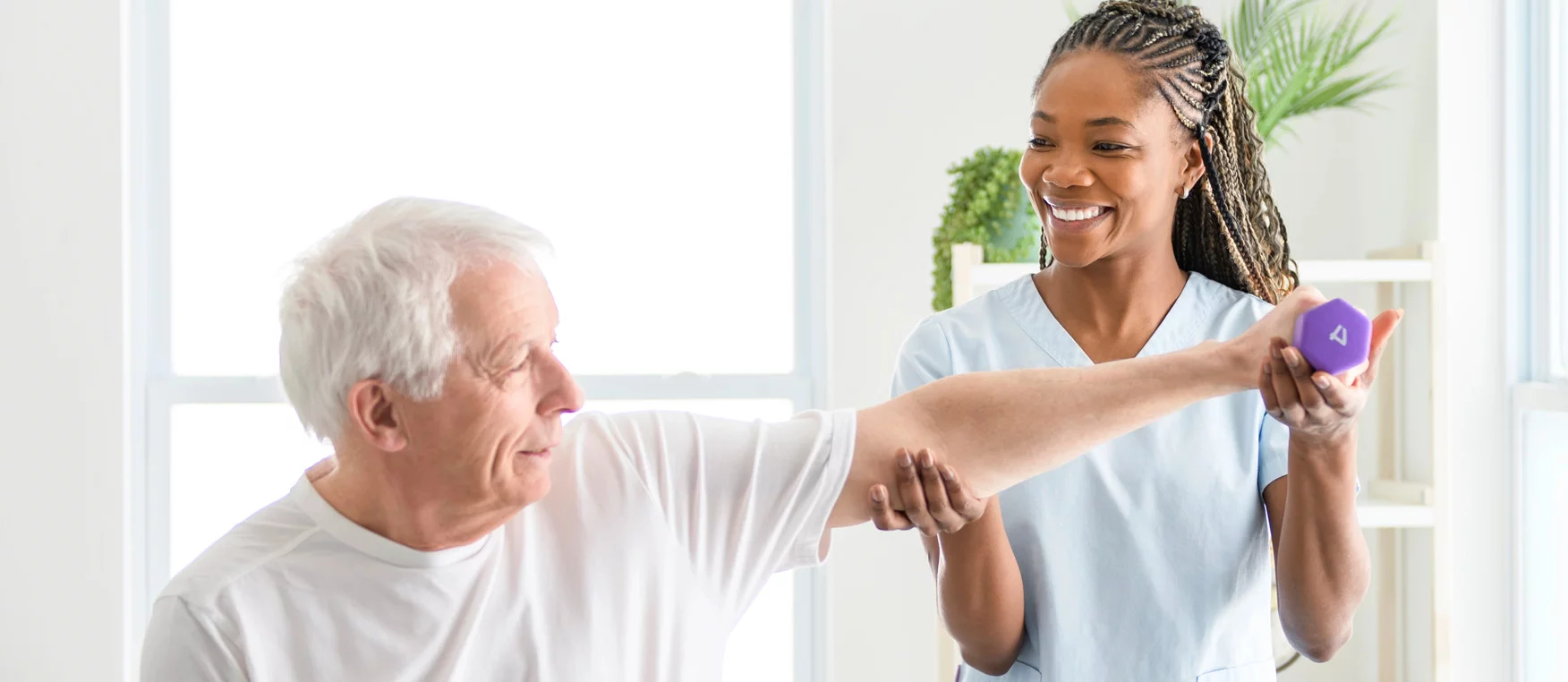 Therapeutin macht mit einem Senior Übungen mit einer Hantel