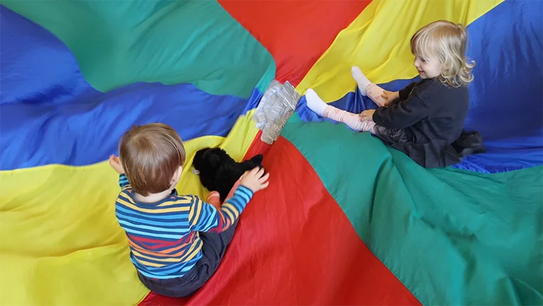 Zwei Kleinkinder spielen gemeinsam auf einem Bodentuch