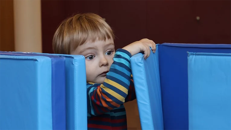 Ein kleiner Junge spielt zwischen den Matten und schaut neugierig hervor