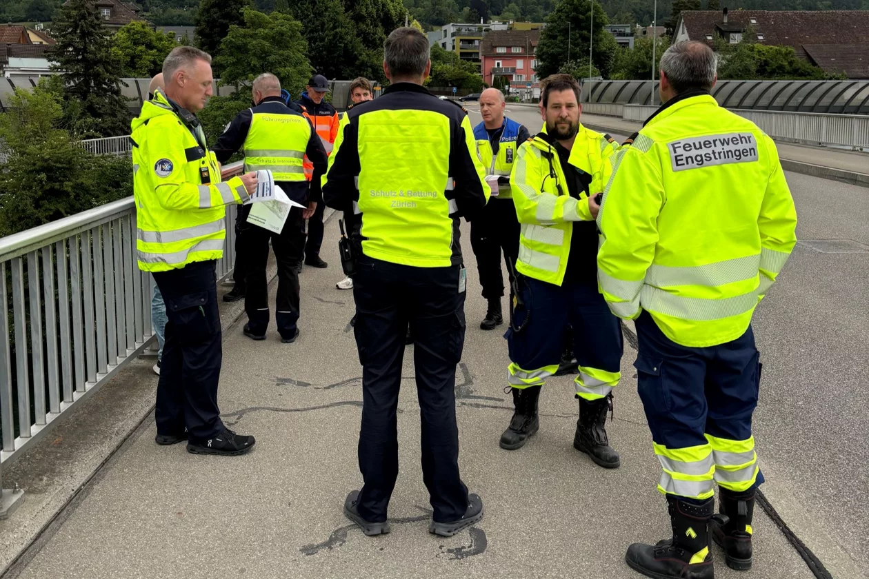 Einsatzkräfte besprechen auf einer Brücke den Ablauf einer Fliesswasserrettung. 