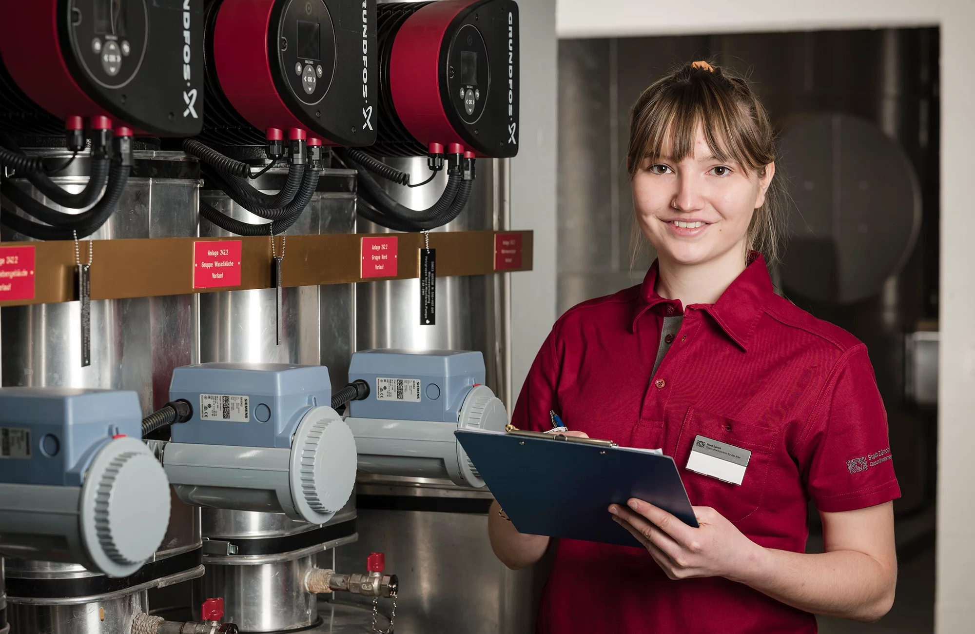 Unterhaltspraktikerin in Ausbildung kontrolliert eine Anlage im Gebäude.