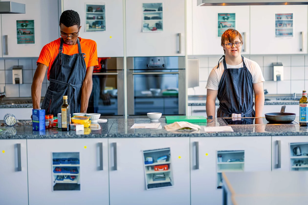 Foto von zwei Schülern in der Schulküche beim Arbeiten.