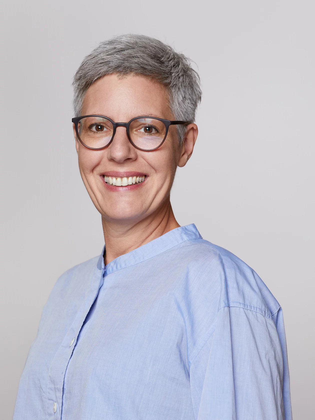Christina Wandeler, eine Frau mit Brille und kurzen grauen Haaren lacht in die Kamera.