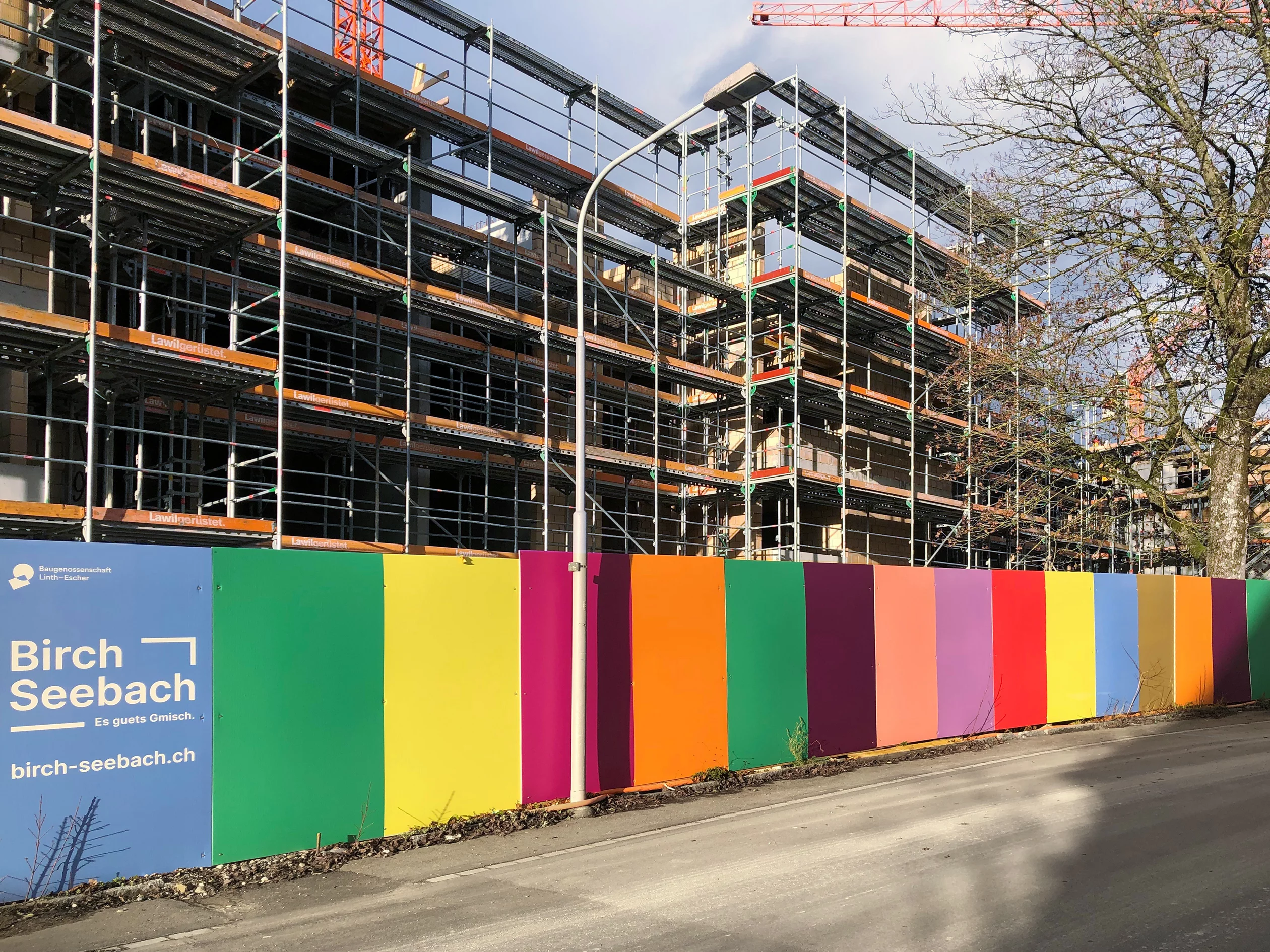 Farbig bedruckte Bauwand vor einer Baustelle