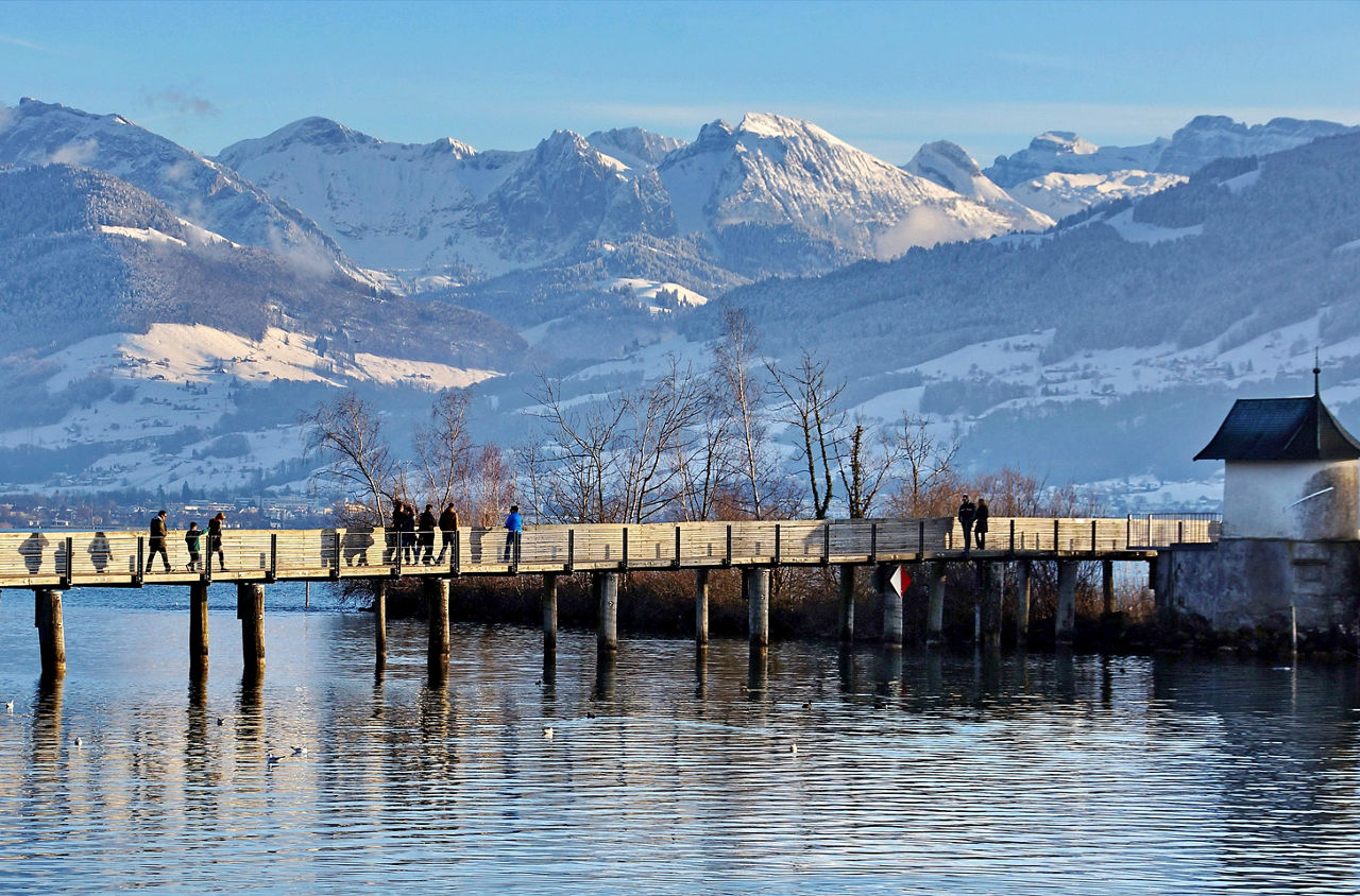 Brücke bei Rapperswil mit verschneiten Bergen im Hintergrund.