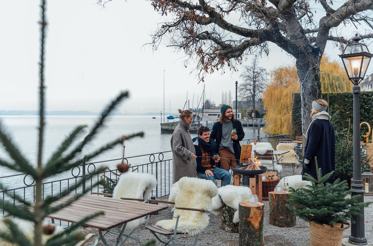 Winterzauber im Garten: Freunde geniessen einen Apéro am Feuer im Garten des Seehotels Sonne in Küsnacht. 