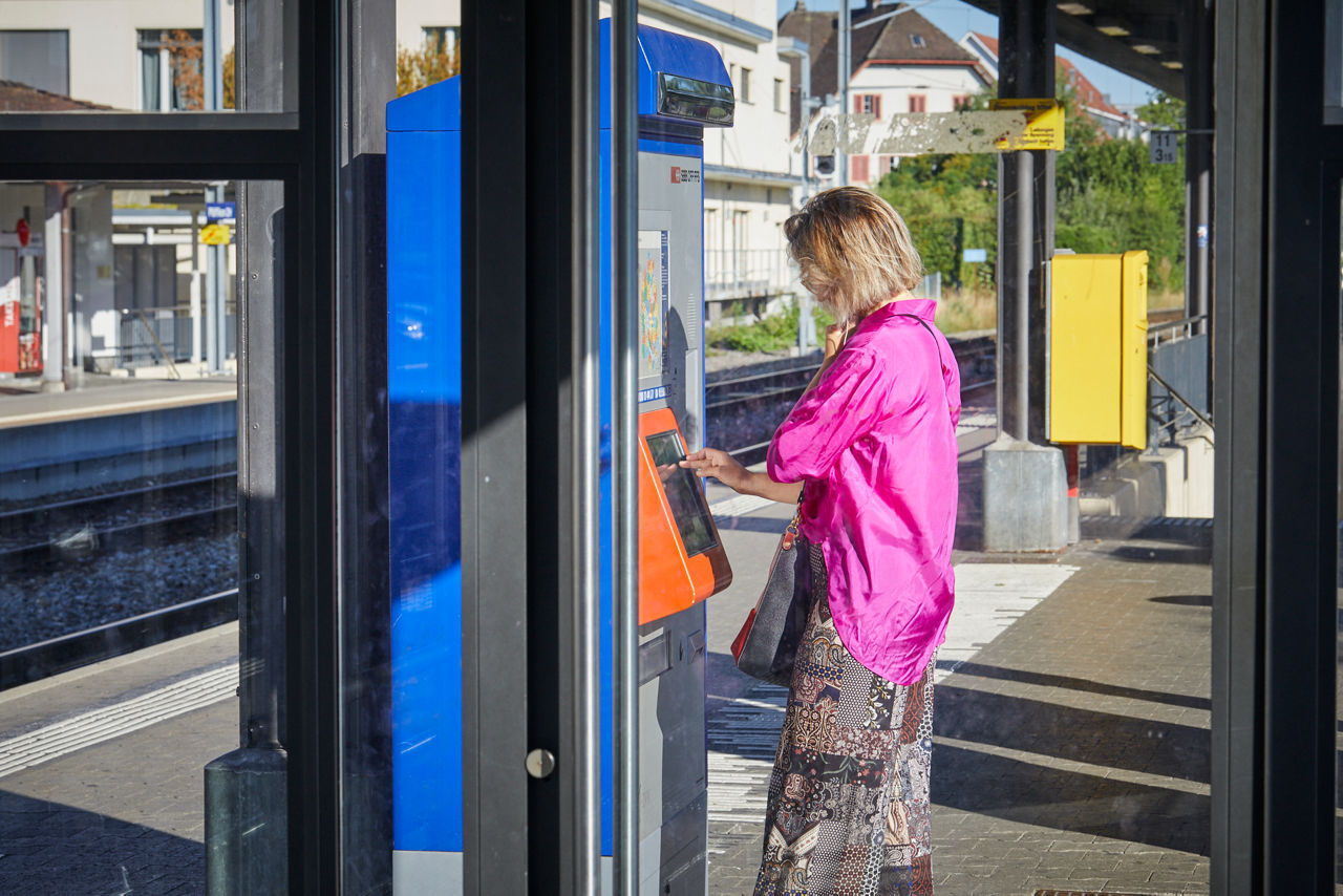 Frau steht am Billettautomat
