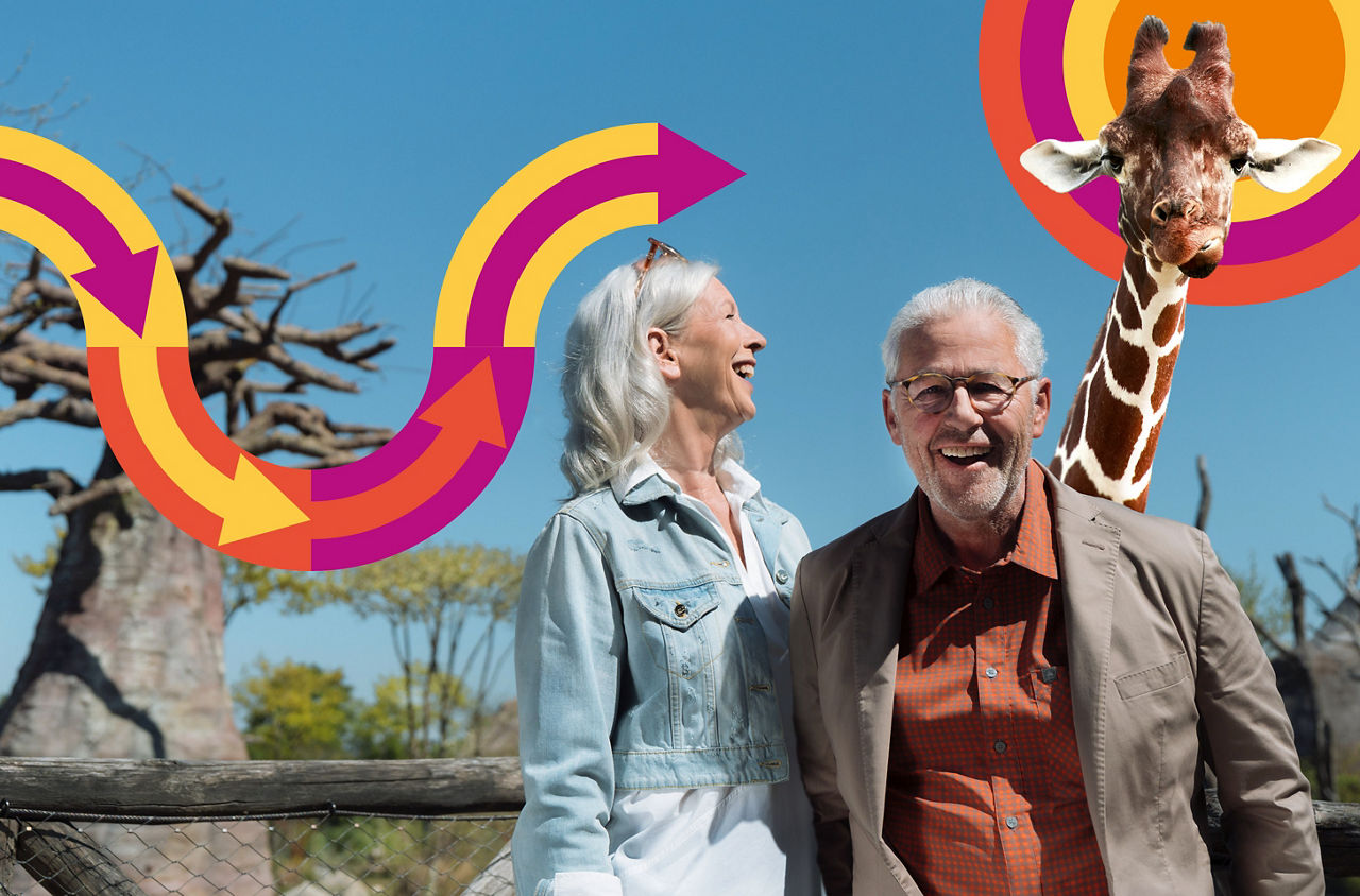 Ein älteres Paar stehen im Zoo und dahiner erscheint eine Giraffe.