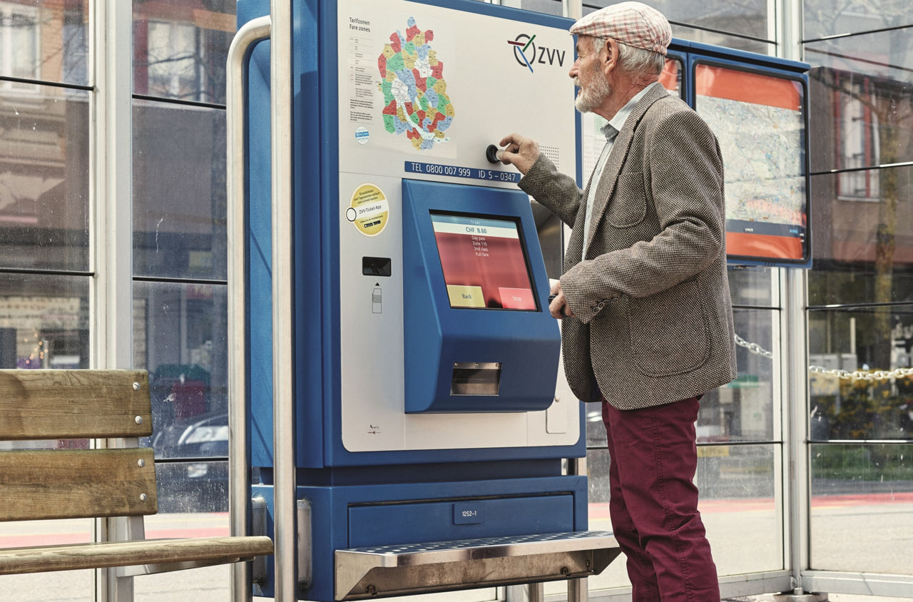 Ein Senior steht am Ticketautomat und kauft ein Billett.