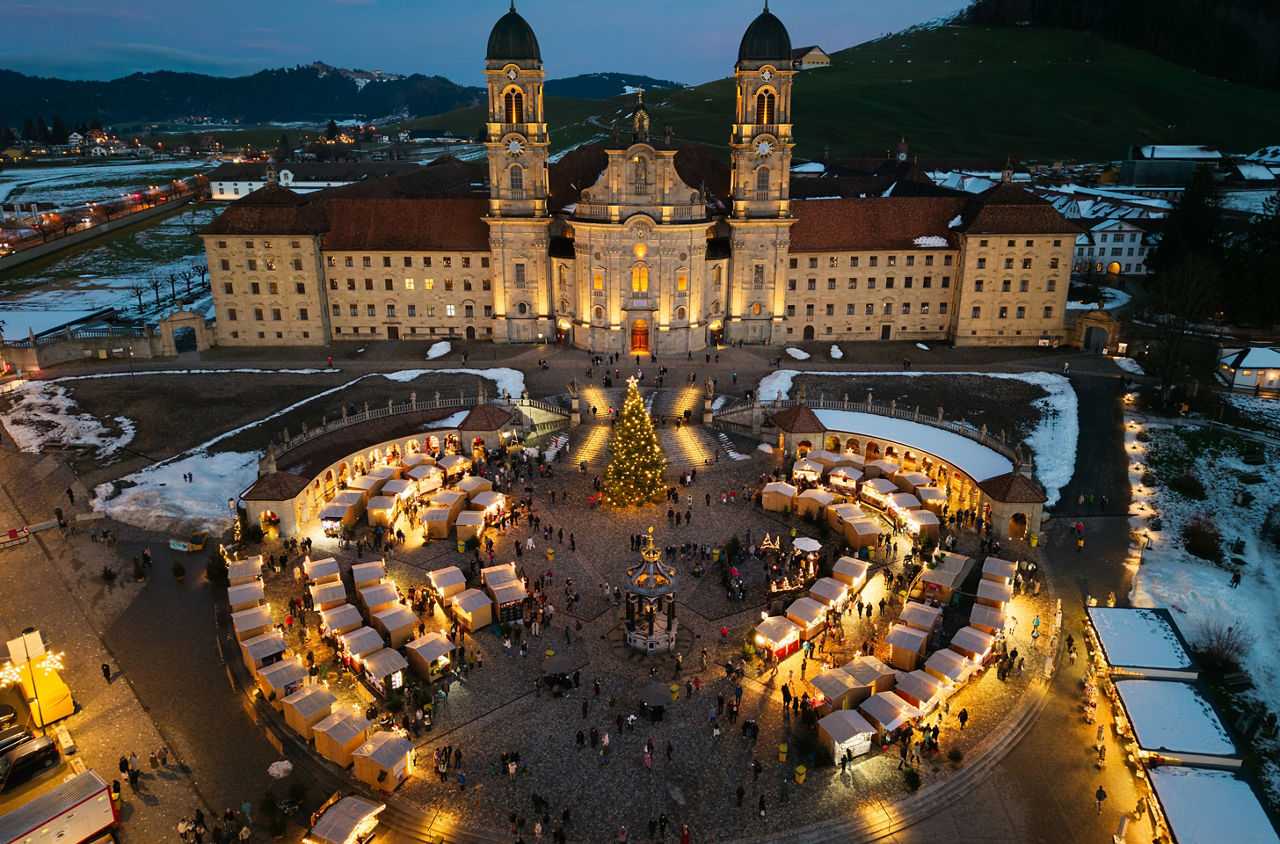 Das Kloster Einsiedeln mit dem Weihnachtsmarkt am Abend. 