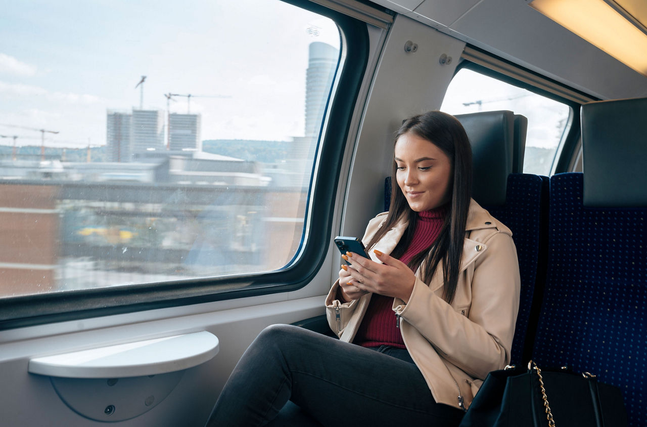 Junge Frau im Zug checkt ihr Handy