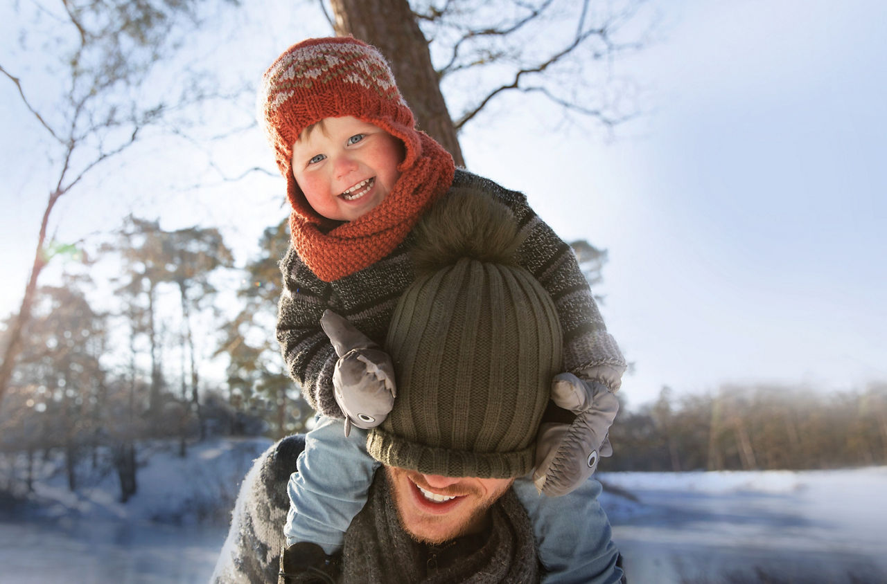 Ein Kind sitzt auf den Schultern eines Erwachsenen. 